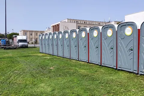 Fila longa de cabines sanitárias INOVSAN num relvado de evento